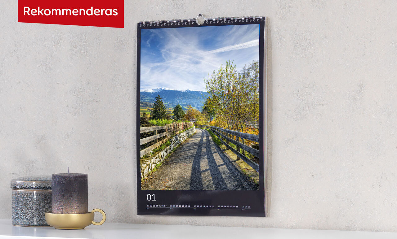 En vacker fotokalender hänger på väggen med en fridfull landskapsbild och en väg genom naturen.