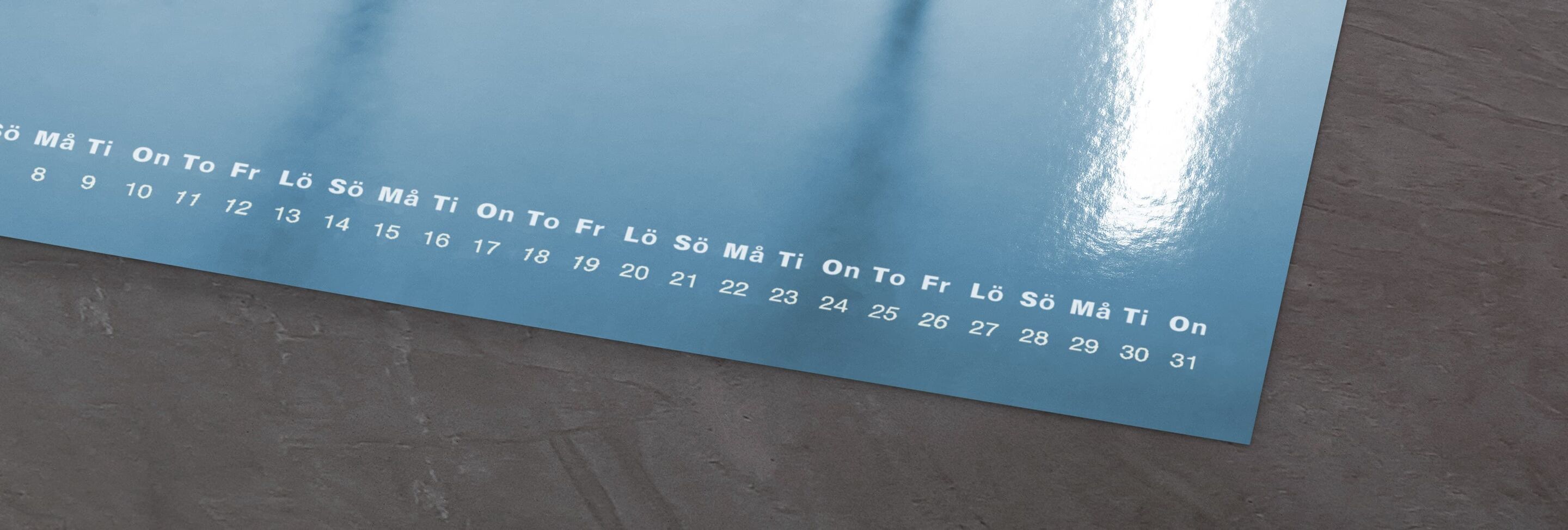 Blå väggkalender med veckodagar och datum, CEWE fotokalender.