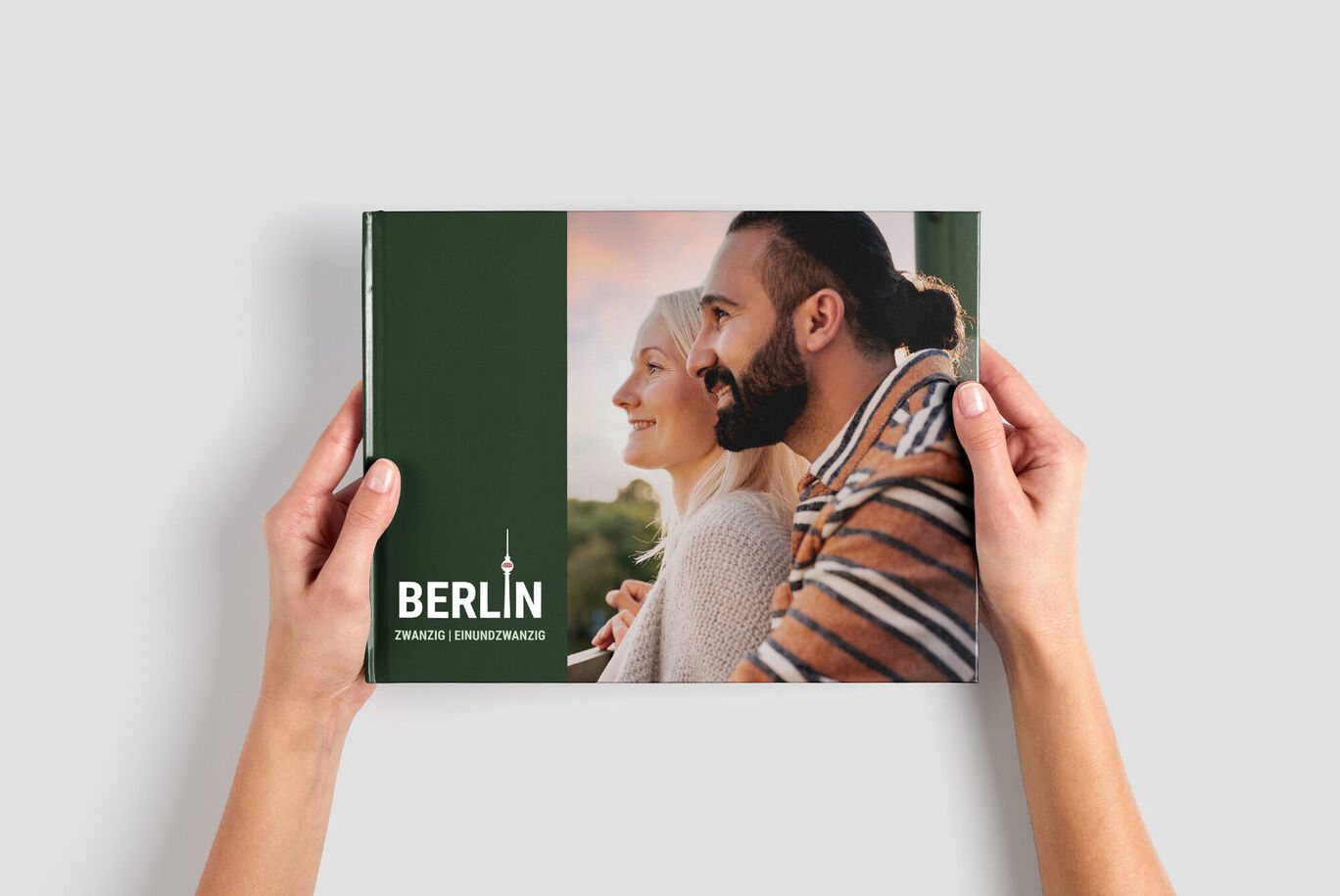 En person håller en CEWE FOTOBOK med en tilltalande design i händerna.