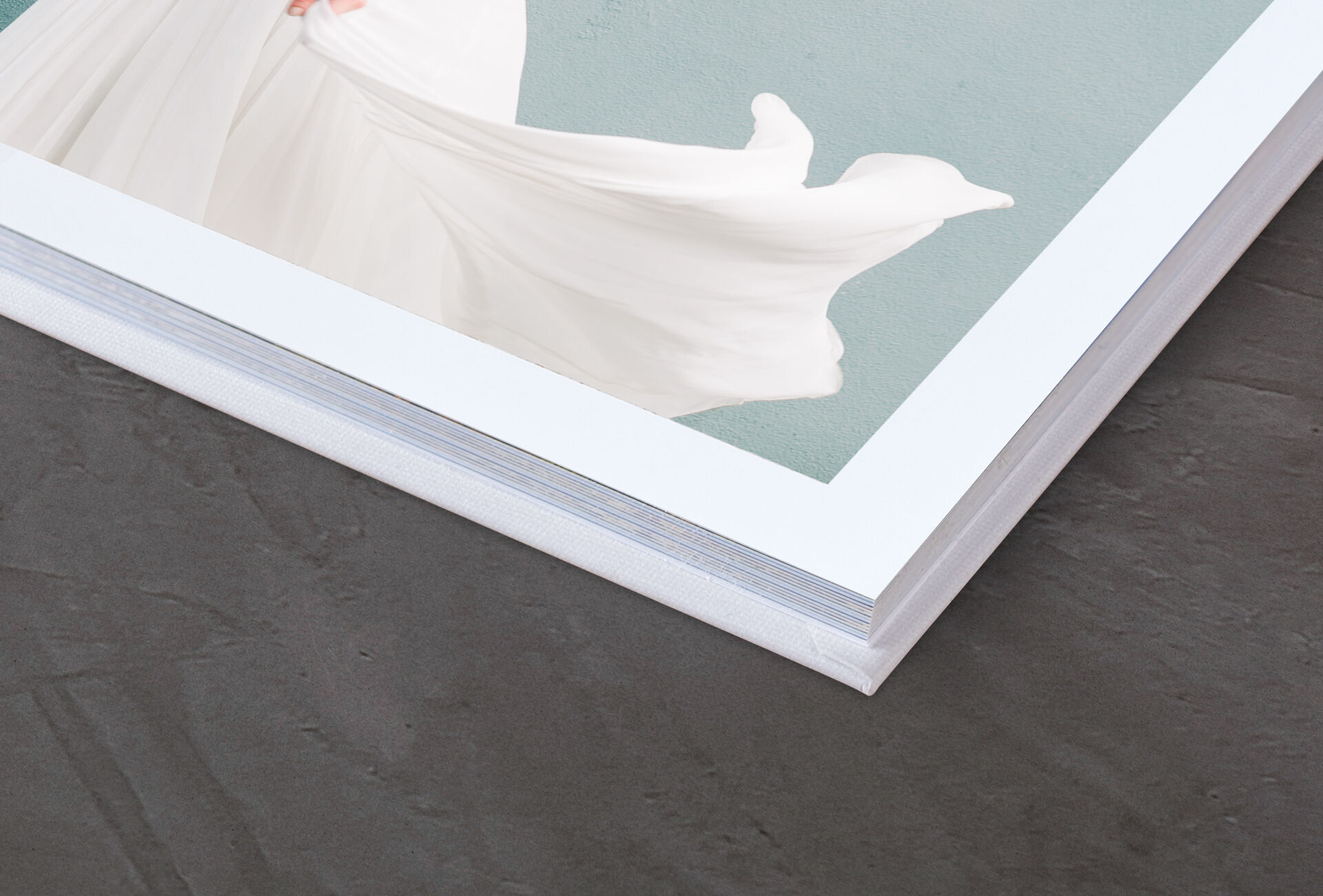 Detaljbild av en CEWE FOTOBOK med ett elegant vitt omslag och en mjuk bakgrund