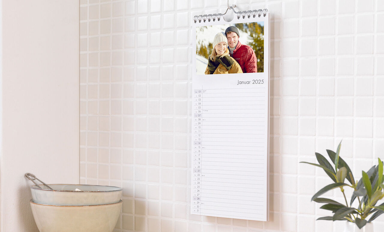 CEWE fotokalender med leende par i januari 2025 på en köksbänk.