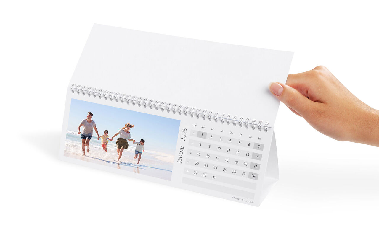 En kalender hålls, i bakgrunden en glad familj på stranden.