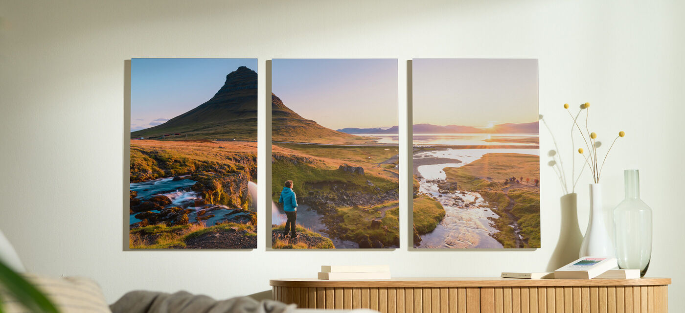 En person i blå kavaj står framför ett naturskönt landskap med berg och flod i mjukt ljus.