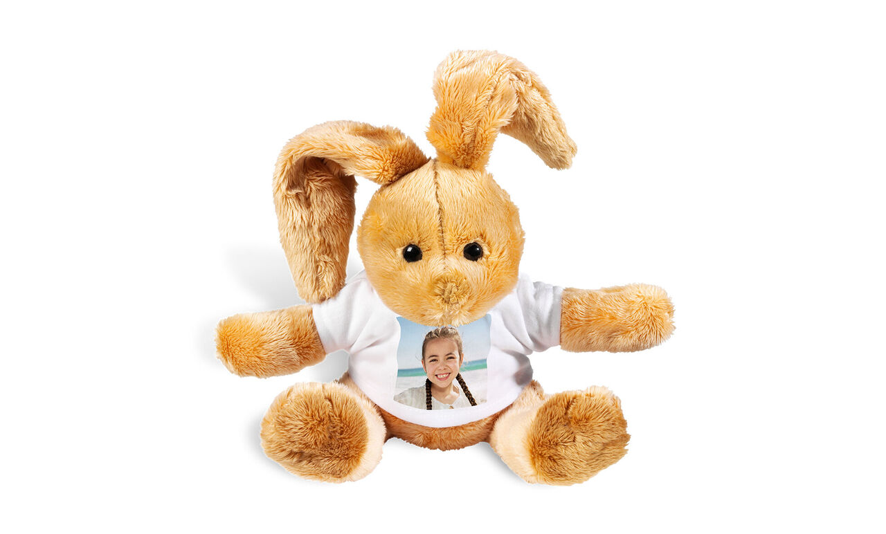 En söt brun plyschkanin med mjuka öron bär en vit t-shirt med foto.