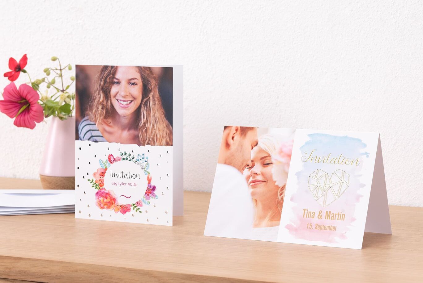 Två kärleksfullt designade inbjudningskort med blommotiv på ett träbord.