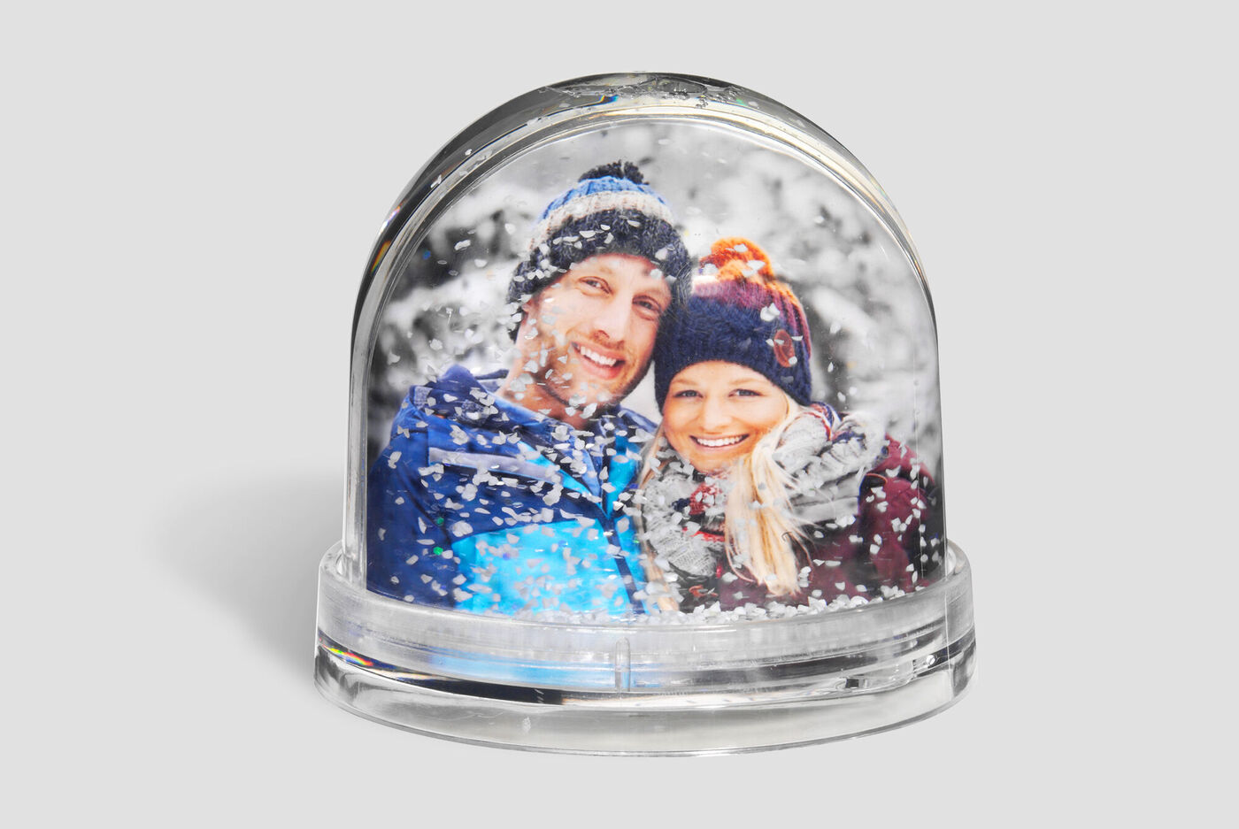 Två personer i en snöglob omgivna av snöflingor.