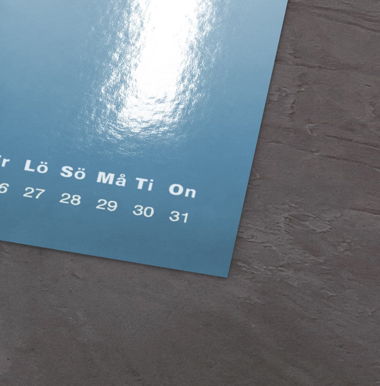 Kalenderblad från CEWE fotokalender i mjuka blå nyanser med framsidan och siffror.