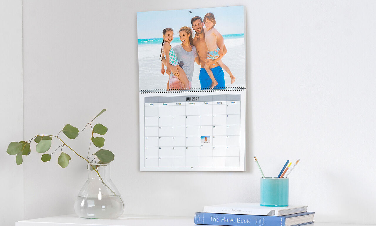 Familj poserar glädjefyllt framför en kalender med semesterbilder.