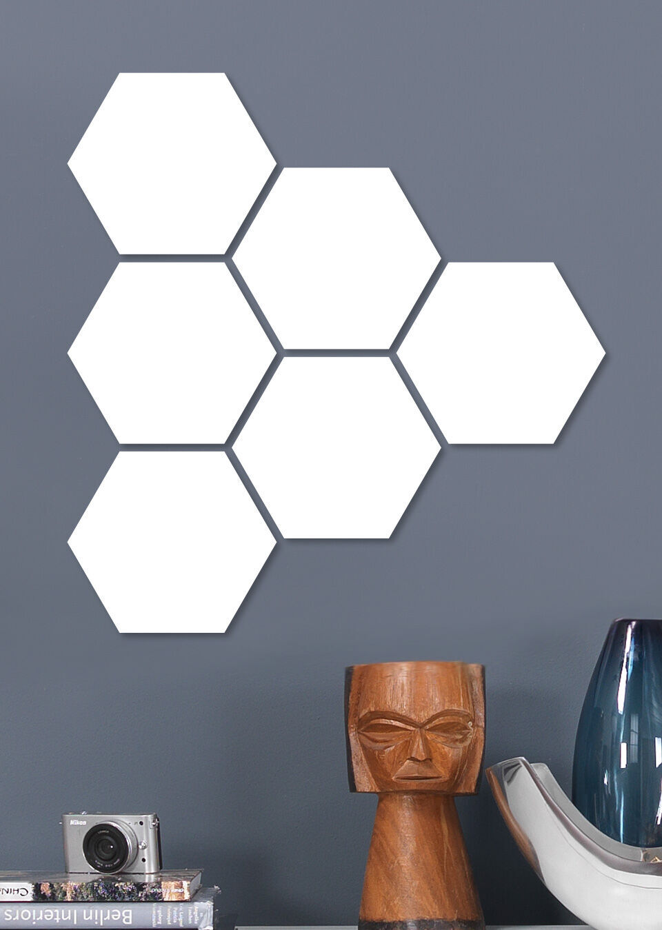 Sex vita hexagonala former på en grå vägg, bredvid en modern lampa och en kamera