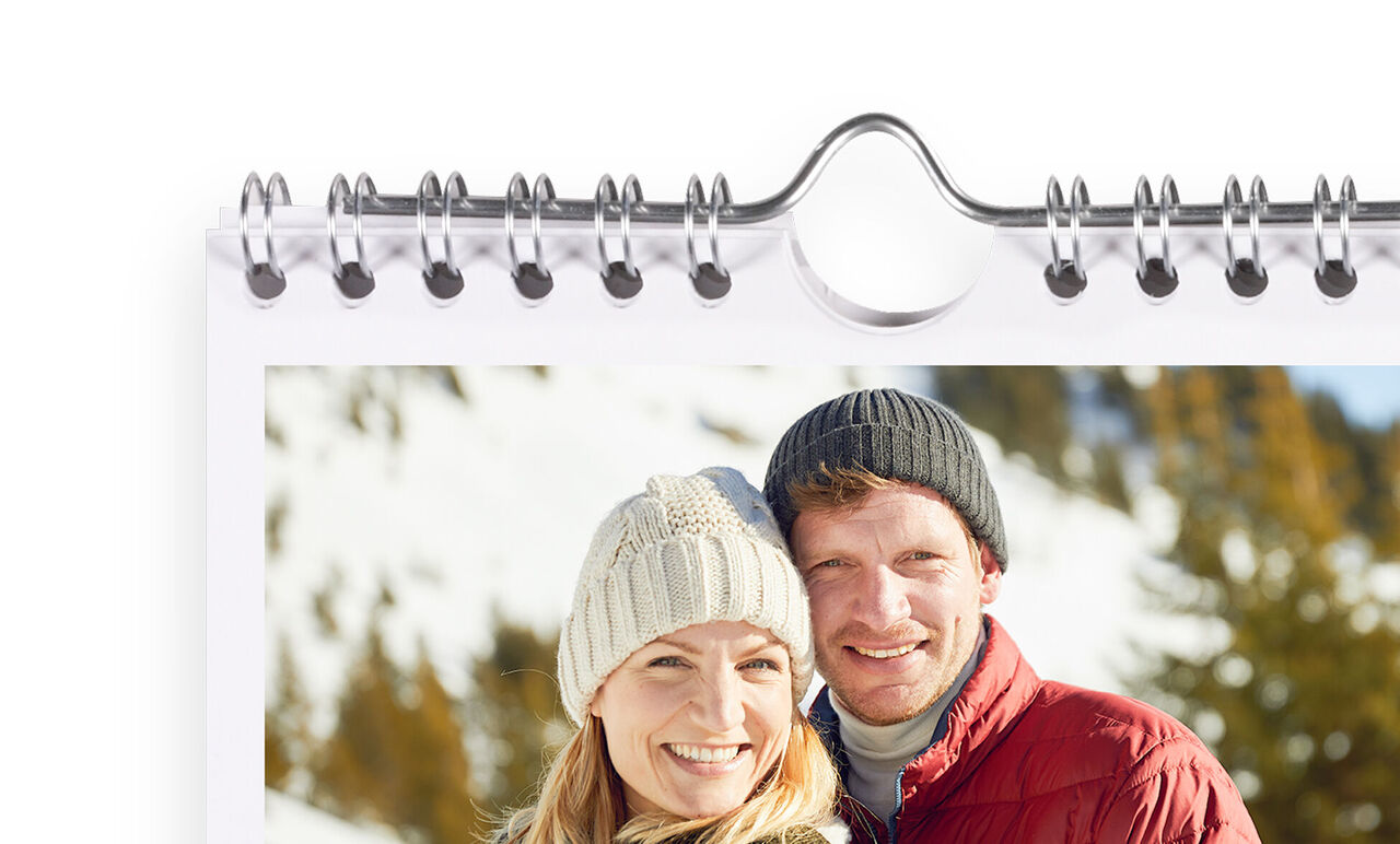 Ett lyckligt par poserar framför ett snöigt bergslandskap i en kalender.