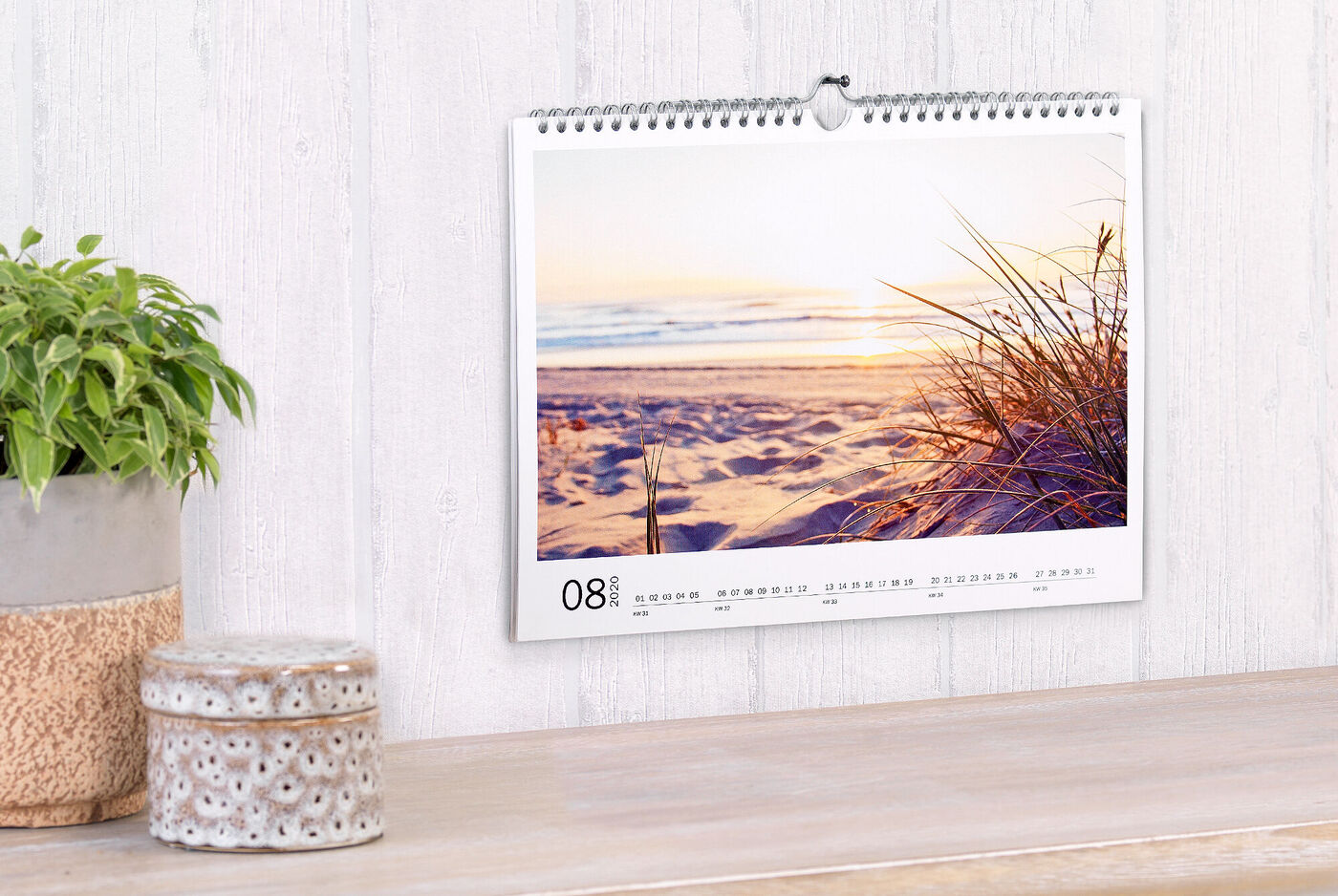 En vacker kalender med en solnedgång på stranden och mjuk gräs i förgrunden