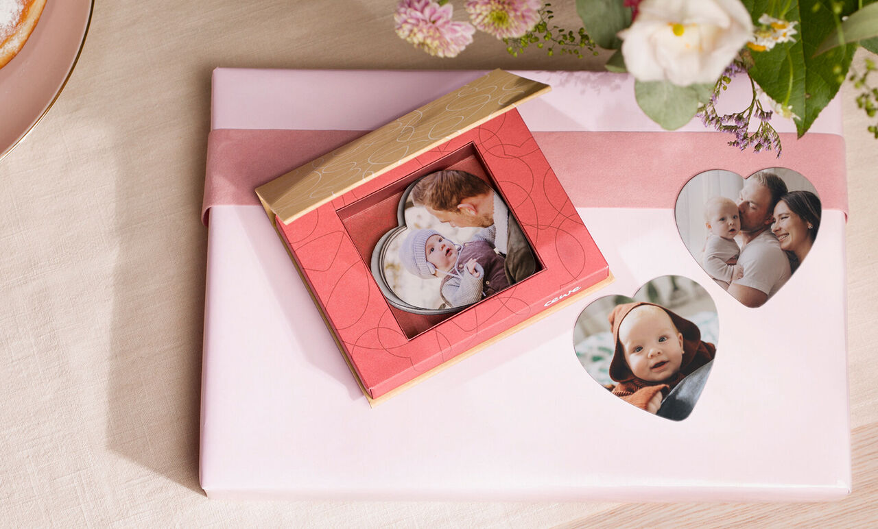 En vacker röd present med fotokort presenteras kärleksfullt, omgiven av blommor. Perfekt för att ge minnen.