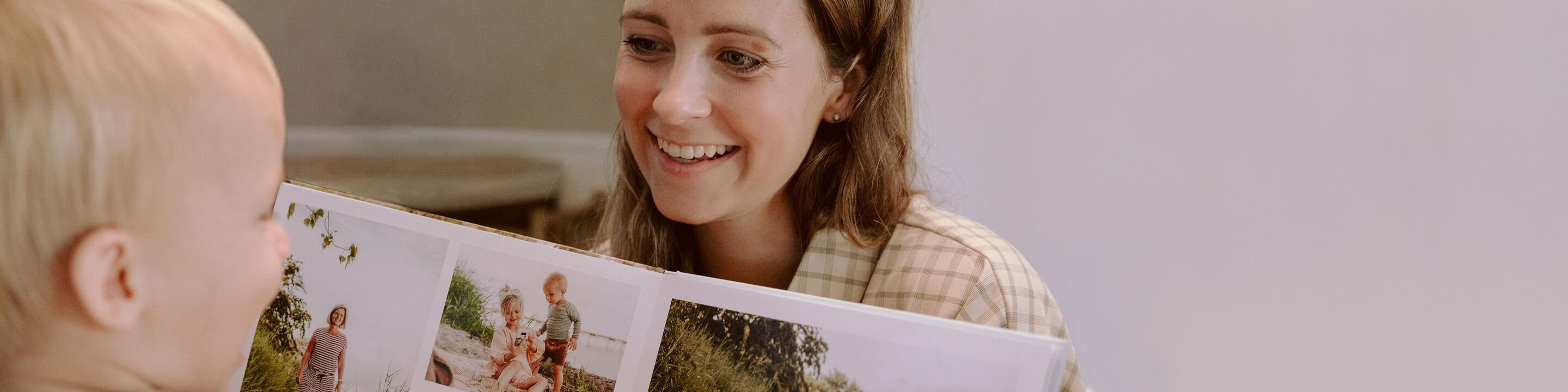 Ett barn visar stolt en CEWE FOTOBOK med färgglada minnen.