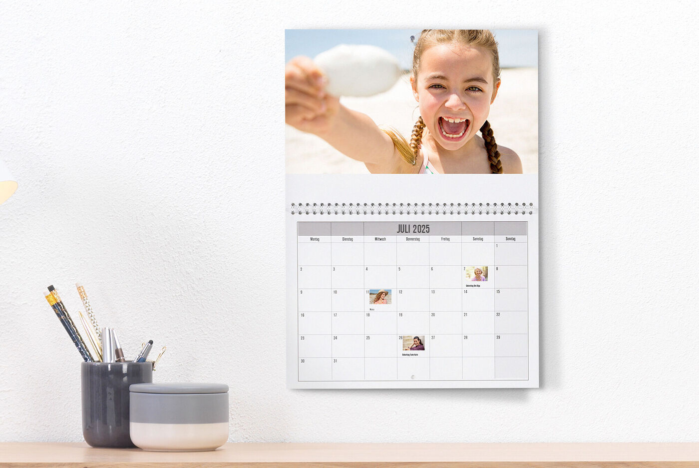En person håller en sked på stranden framför en kalender.