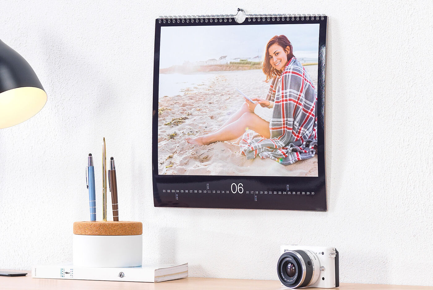 En CEWE fotokalender med ett ögonblick av en person som sitter på stranden och läser en bok.