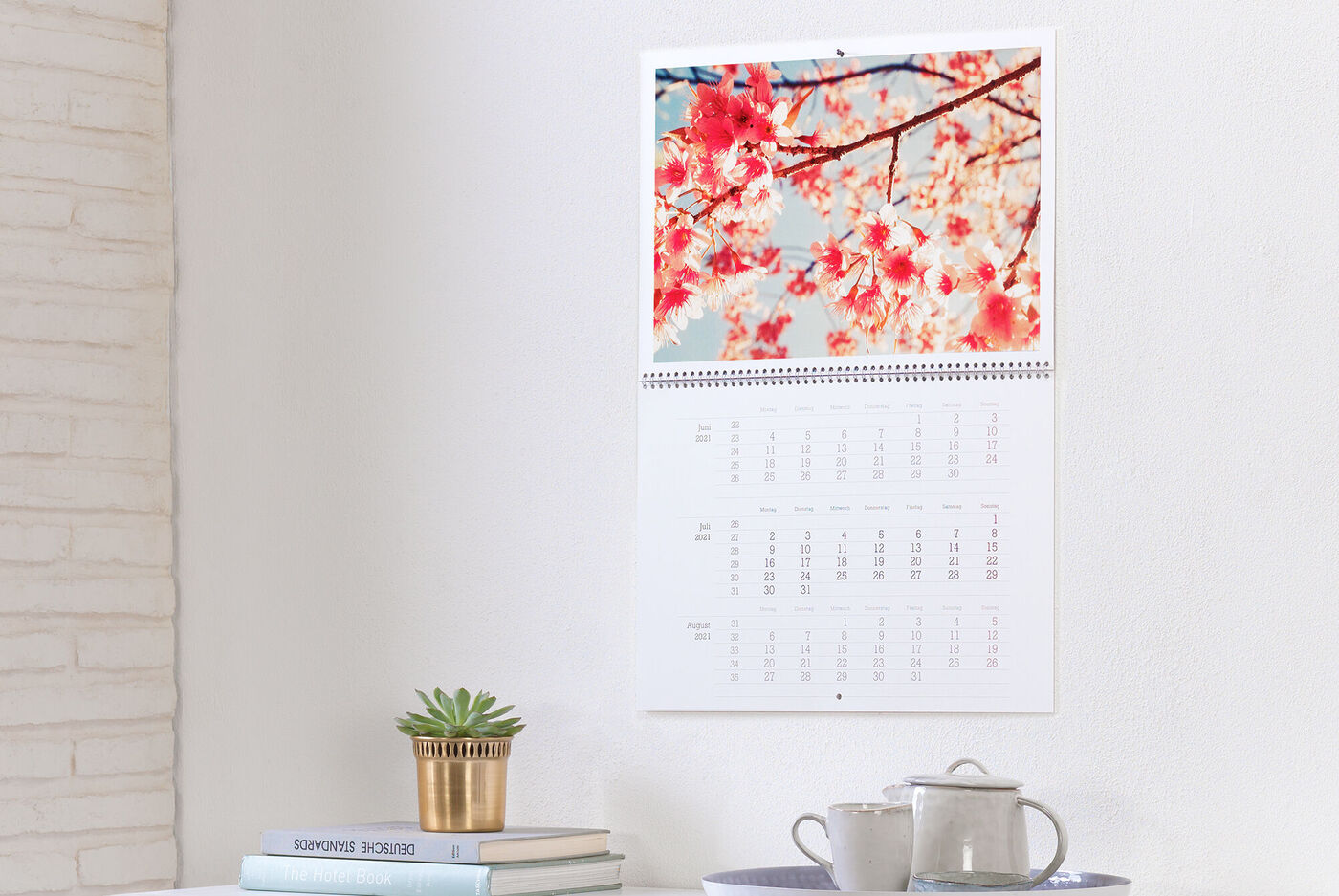 En CEWE fotokalender med körsbärsblommor som hänger på en vit vägg.