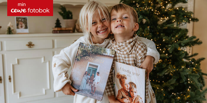 Två barn håller stolt fotoböcker.