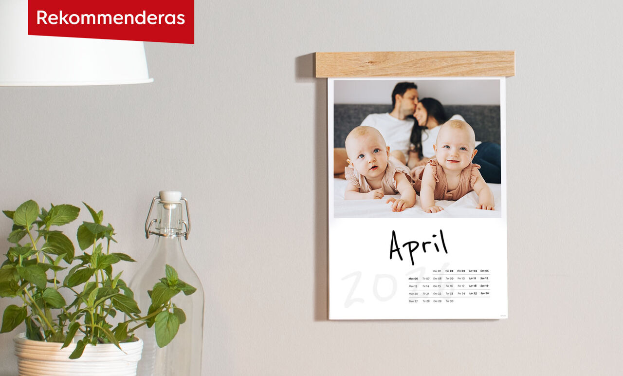 En väggkalender med foto av två bebisar och månaden april