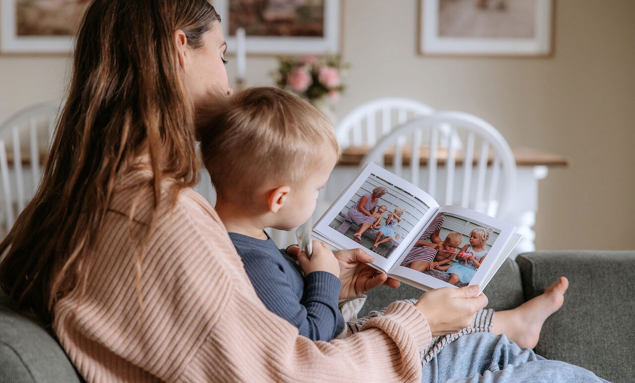 En kärleksfull mamma läser med sitt barn i en fotobok.