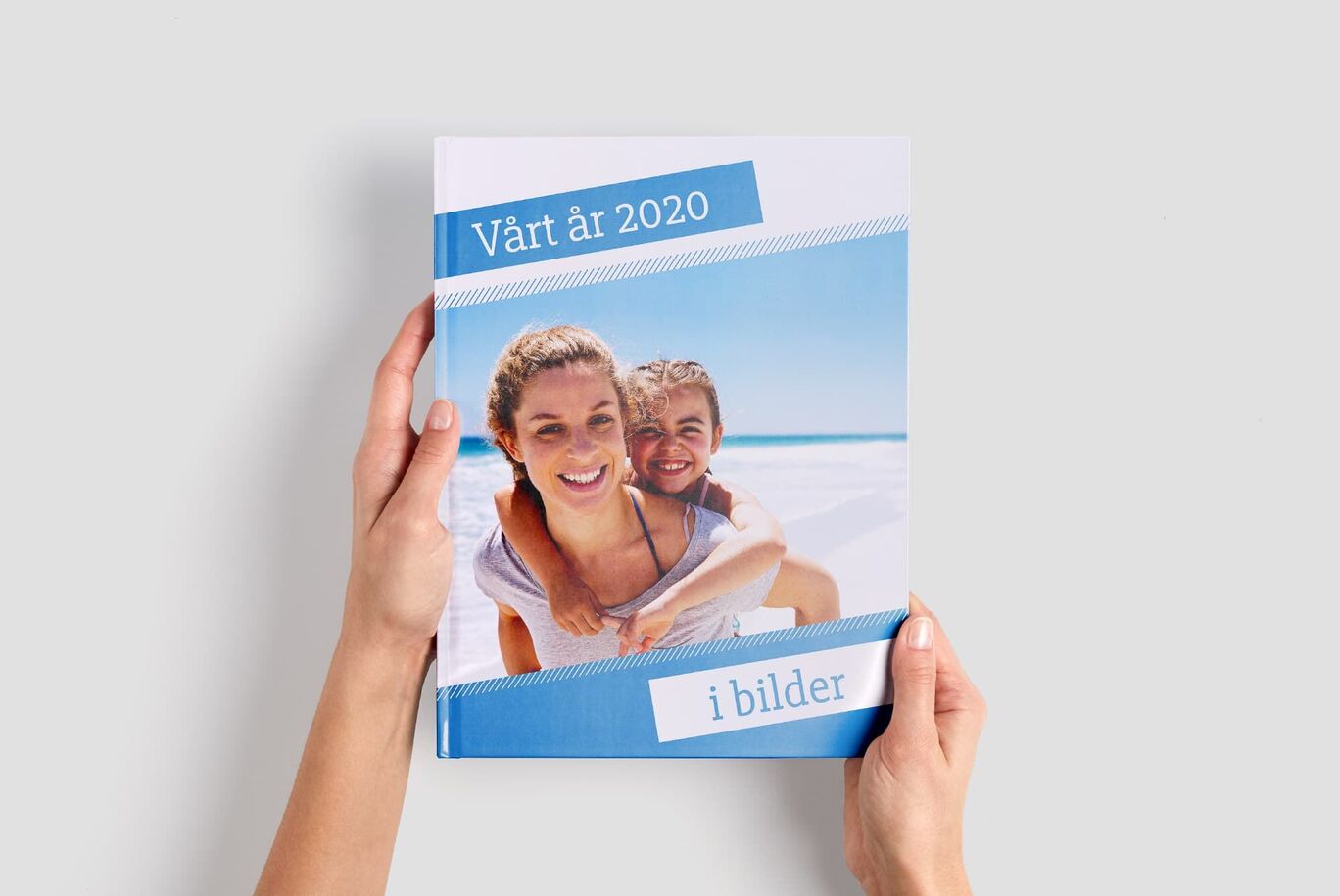 Händer håller en personlig fotobok med strandmotiv.