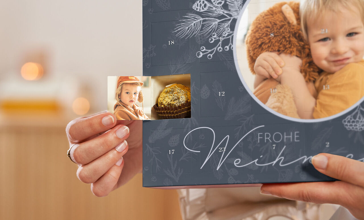 En person håller ett julalbum med ett litet foto och en bild av en gyllene muffin.