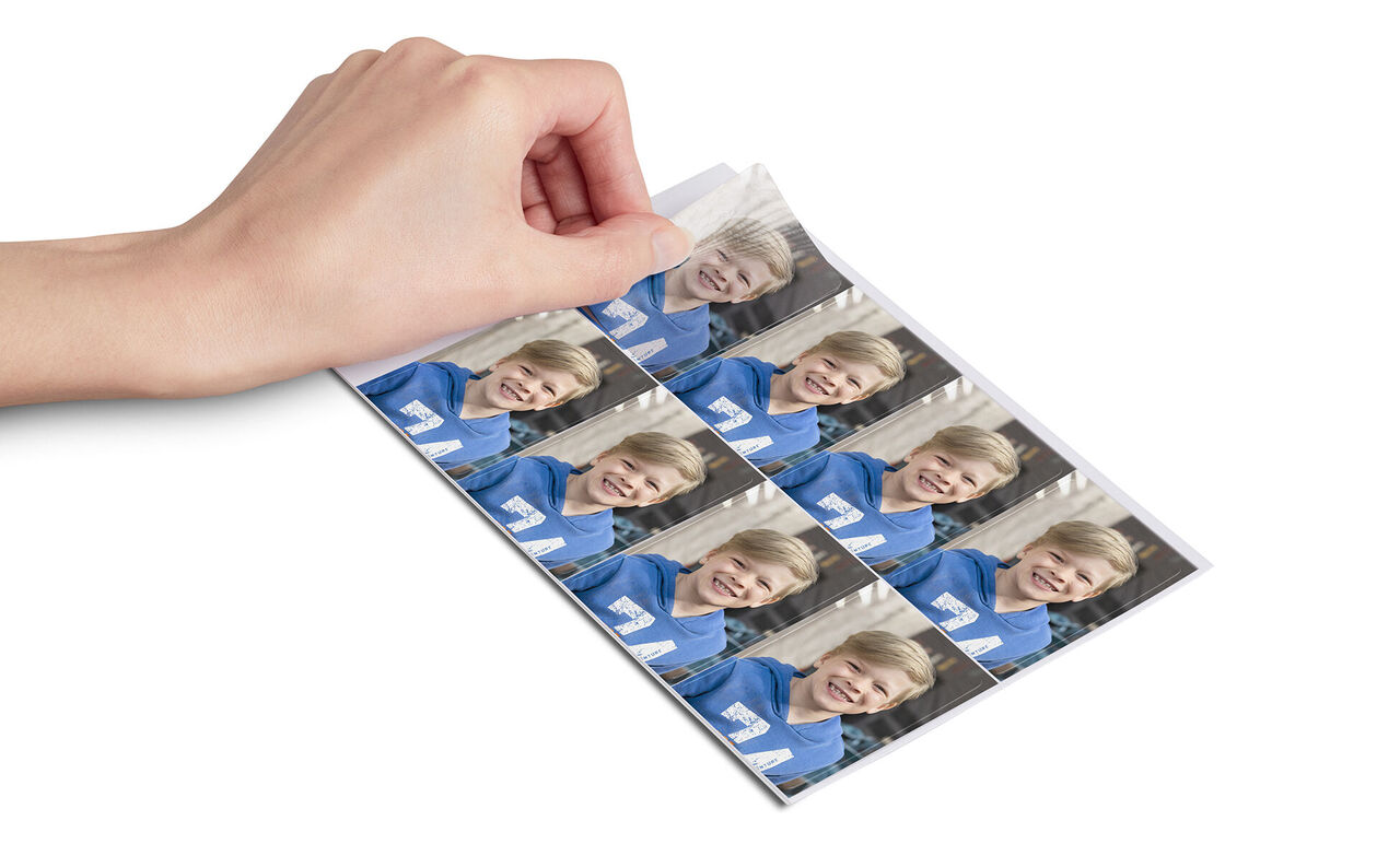 En hand visar fotoutskrifter av en pojke i blå kläder.